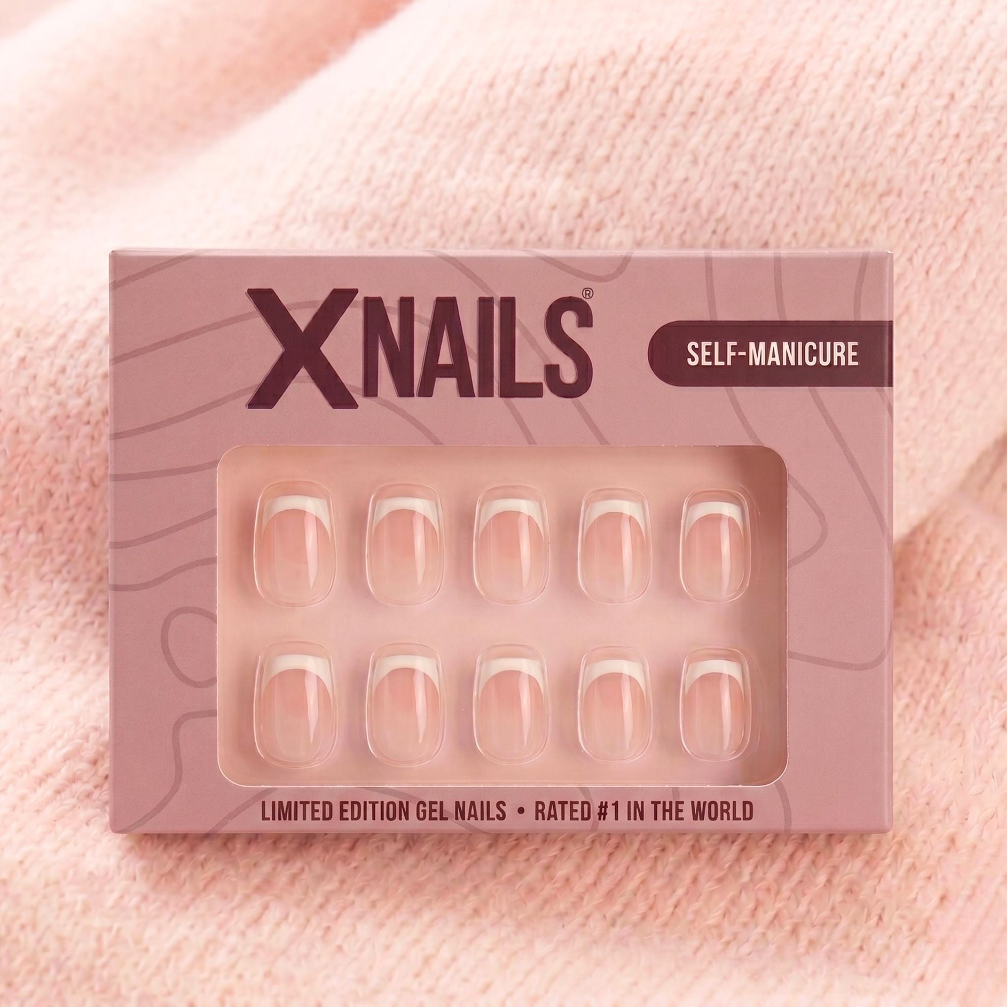 XNails-eske med hvite franske korte square press-on negler mot rosa strikket bakgrunn