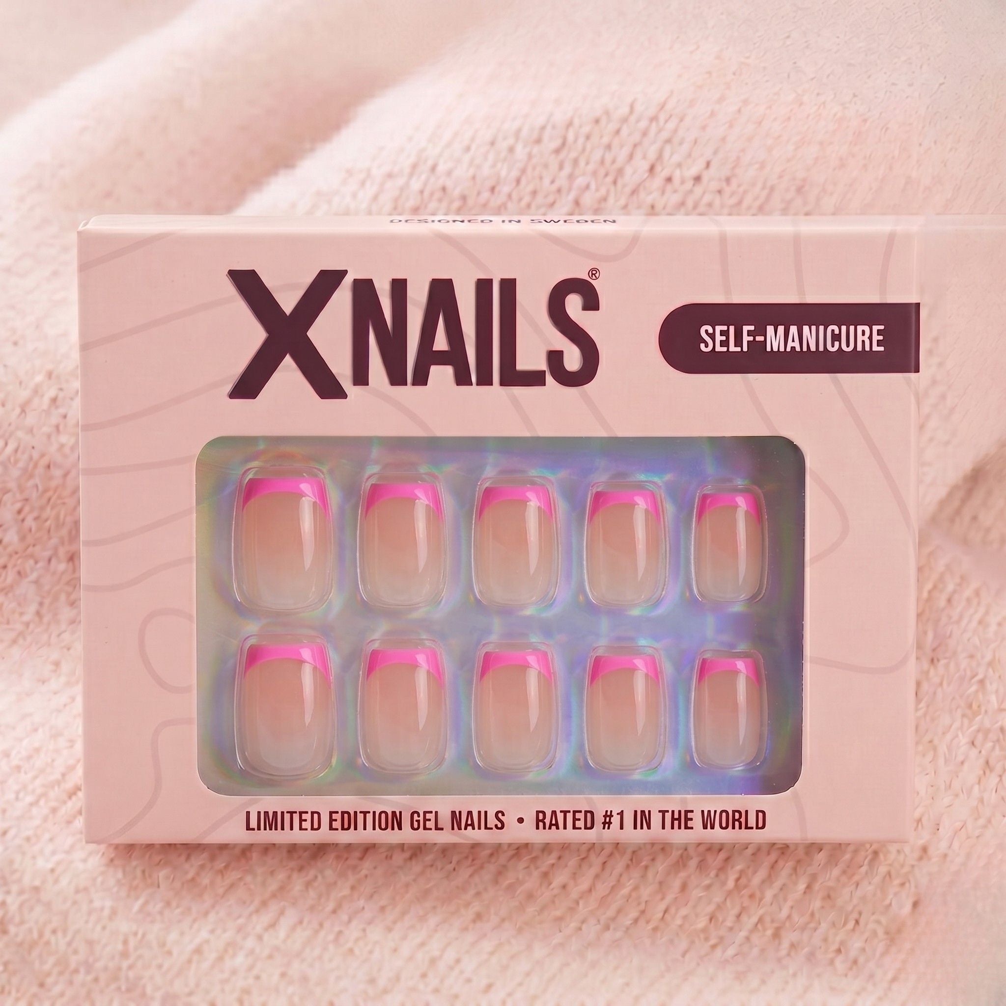 XNails-eske med rosa franske korte square press-on negler mot rosa strikket bakgrunn