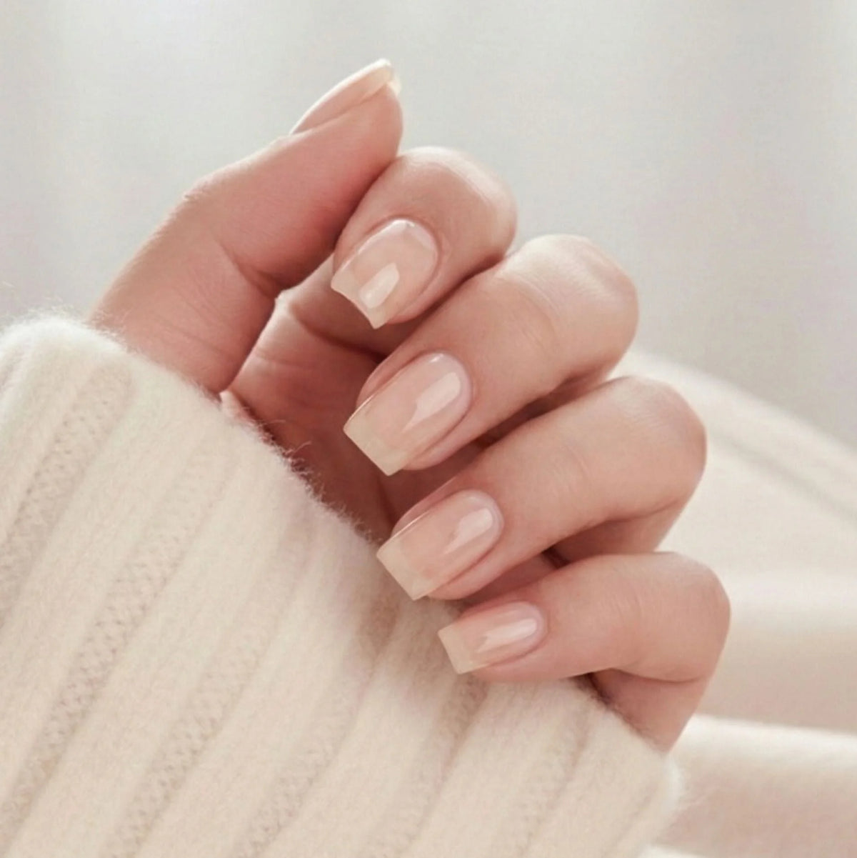 Heavenly Halo press-on negler – korte square løsnegler i myk nude med subtilt skimmer mot beige genser