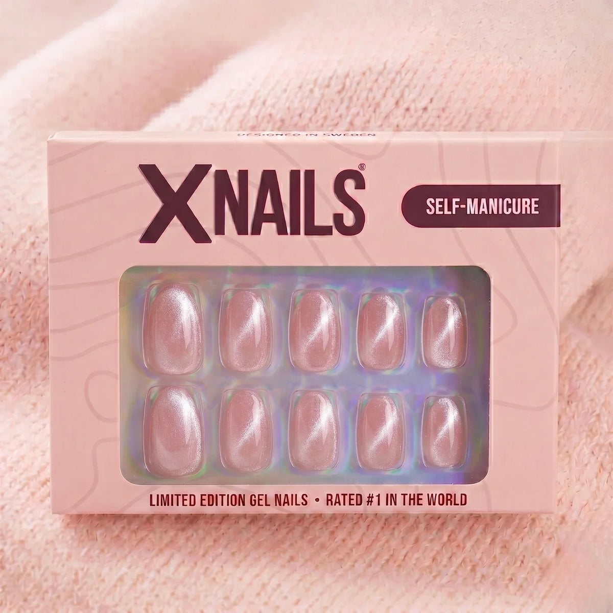 XNails-eske rosa chrome almond press-on negler mot strikket rosa bakgrunn