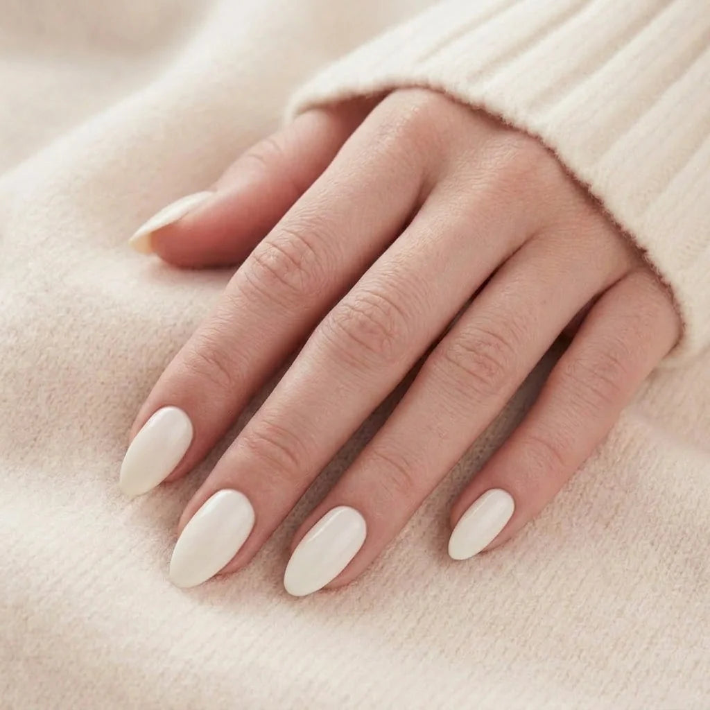 Satin Snow løsnegler nærbilde – kremhvite mandelnegler mot beige cashmere-genser