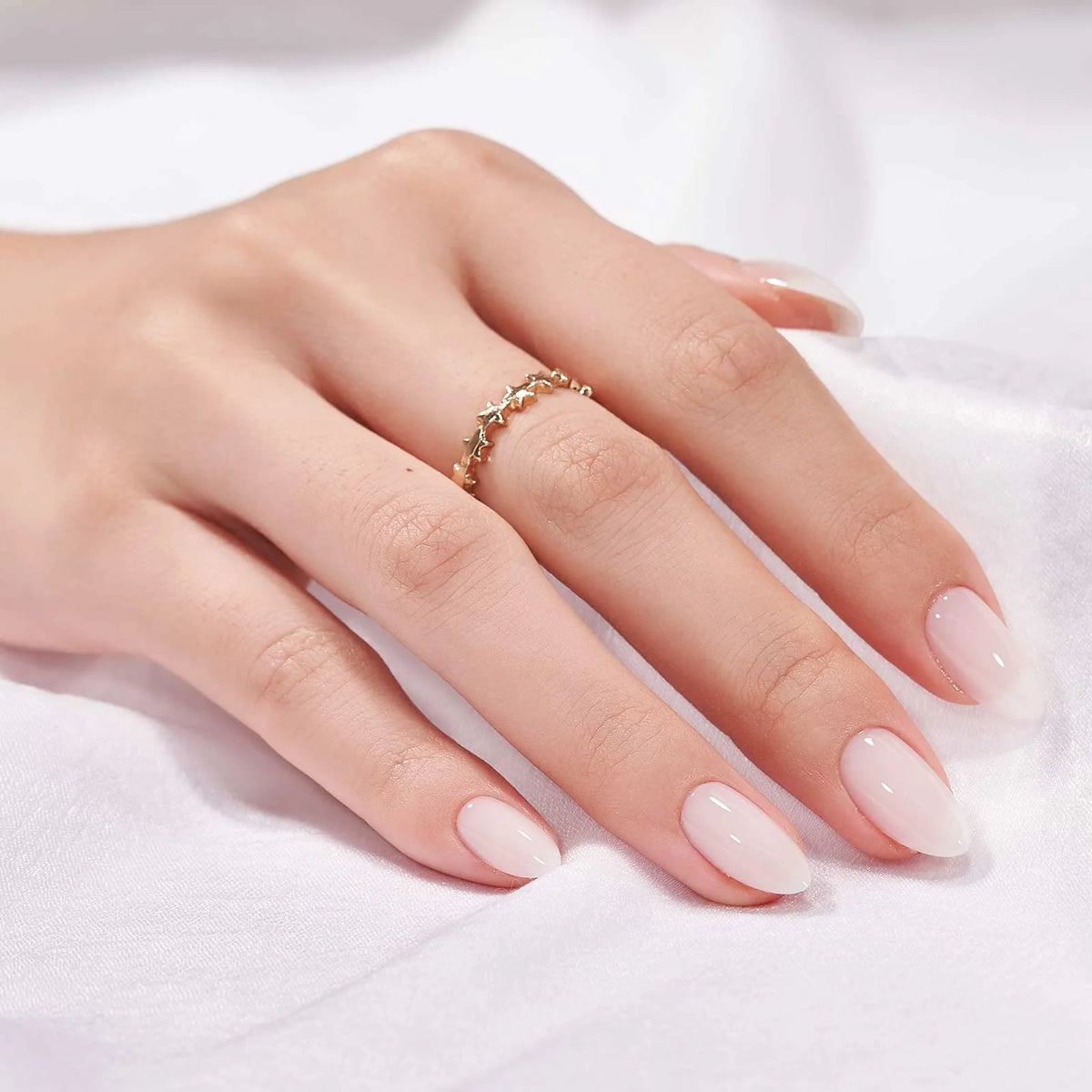Satin Snow press-on negler styling – nude mandelnegler med gullring mot hvit sateng