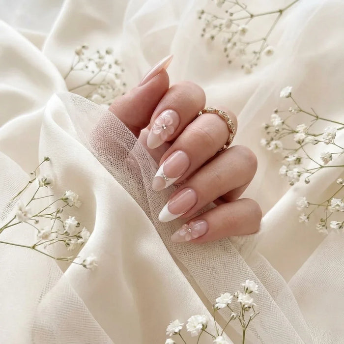 Brudens hand med Bridal Bloom press-on naglar på elfenbenssilke