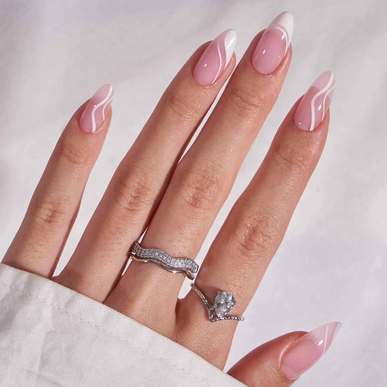 Winter Whirl press-on naglar närbild – mandelformade gelénaglar med silverringar och vit blus