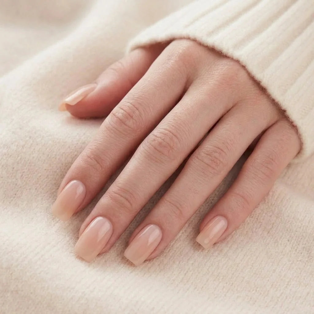 Heavenly Halo løsnegler nærbilde – korte square gelénegler i nude med pearl-glans mot beige strikket bakgrunn