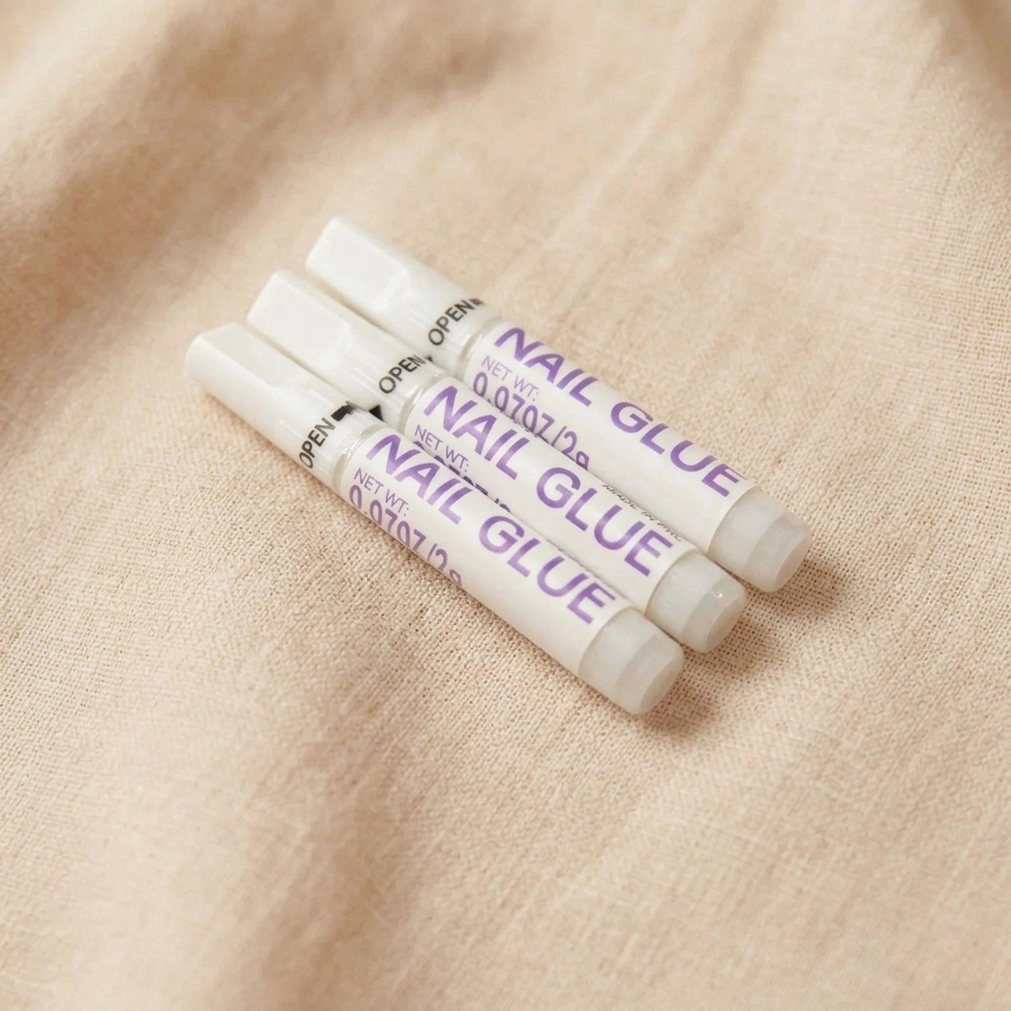 XNails Nail Glue neglelim på beige bakgrunn
