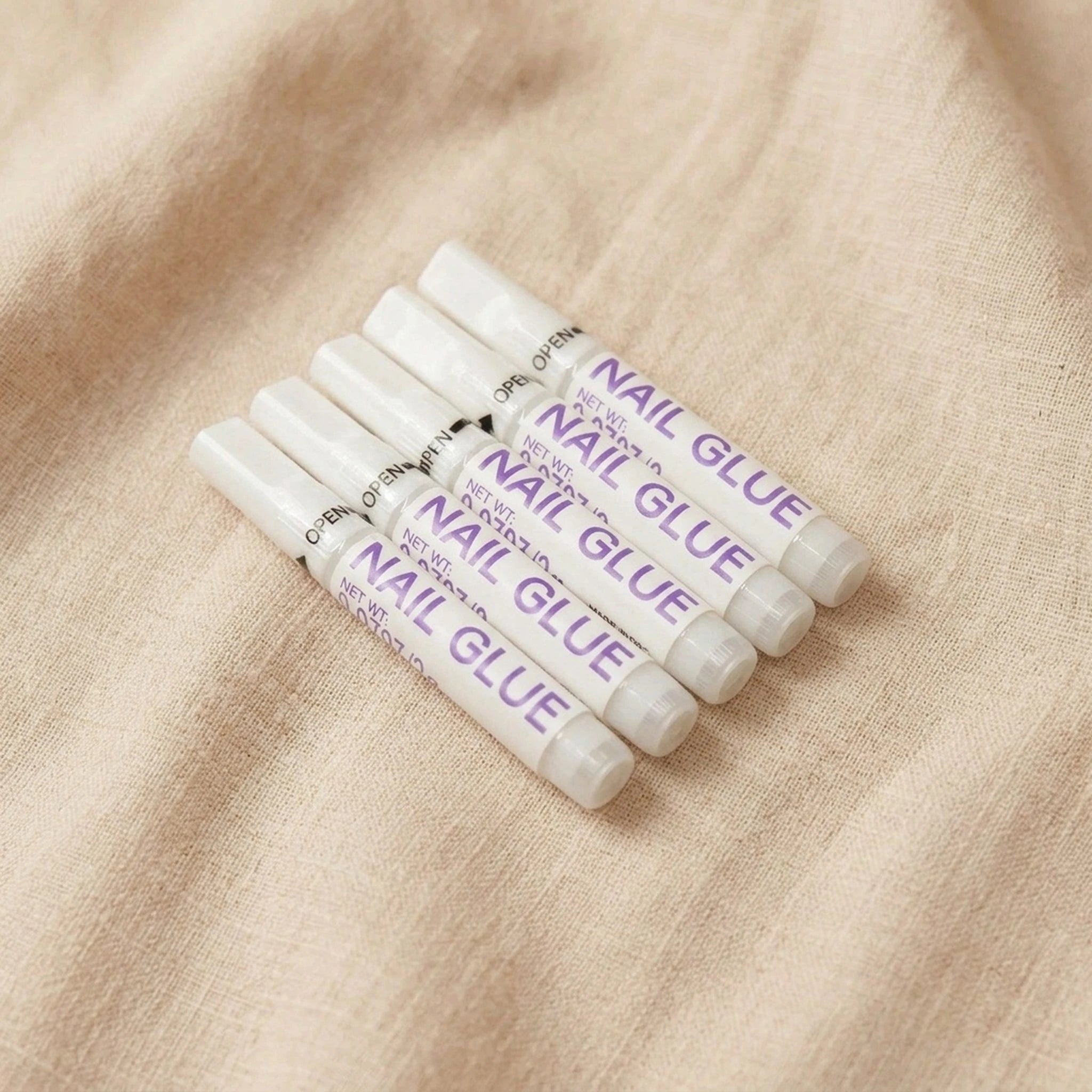 XNails Nail Glue neglelim på beige bakgrunn