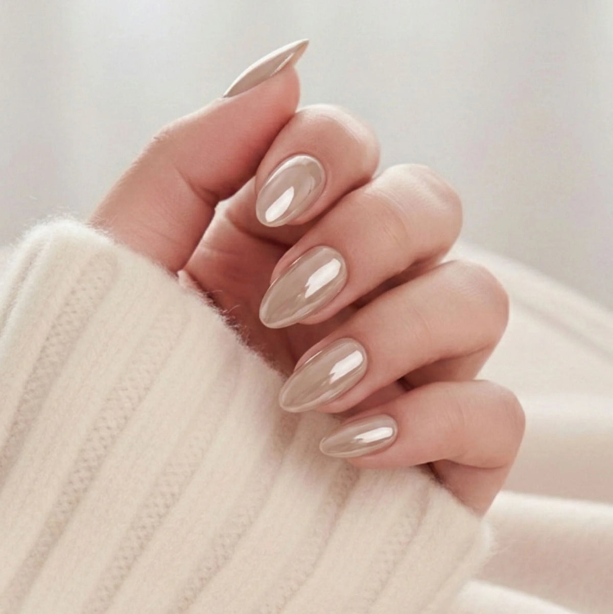 Pearly Perfection press-on negler – mandelform i pearl taupe med metallisk glans mot kremhvit strikket genser