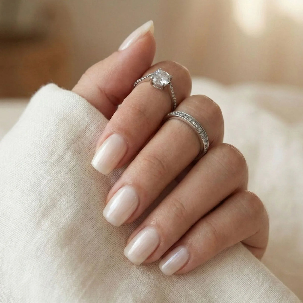 Pure Pearl gelénegler nærbilde – kort square i pearl nude med hvit bluse og sølvringer
